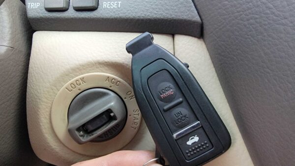 Toyota/Lexus smart key fob near ignition switch showing lock/unlock and panic buttons – immobilizer programming