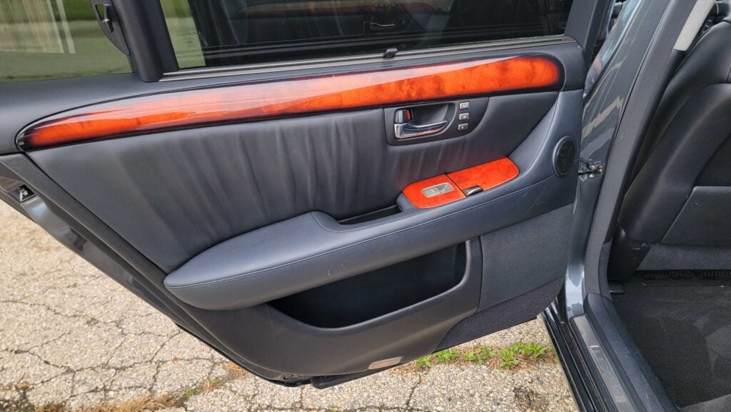 Interior rear driver door panel of 2006 Lexus LS430 ULTRA showing controls and leather finish